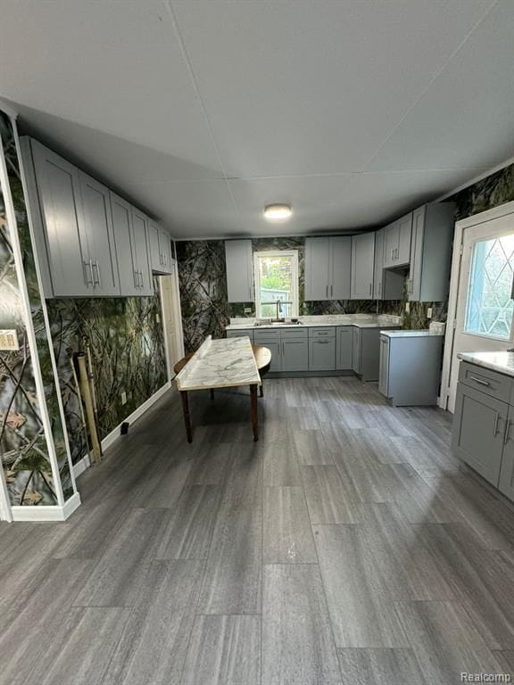 kitchen featuring light countertops, a sink, gray cabinetry, and wood finished floors