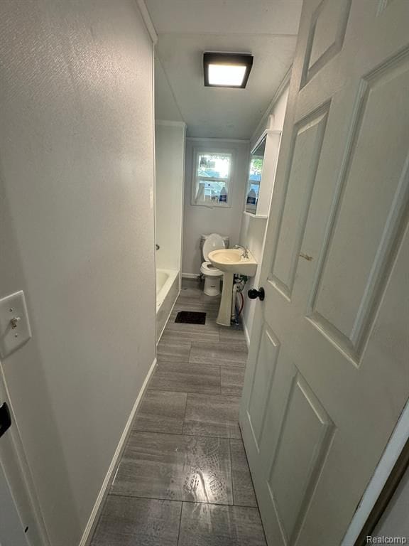 bathroom featuring a sink, wood finished floors, toilet, and baseboards