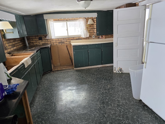 kitchen featuring tasteful backsplash, dark floors, and freestanding refrigerator