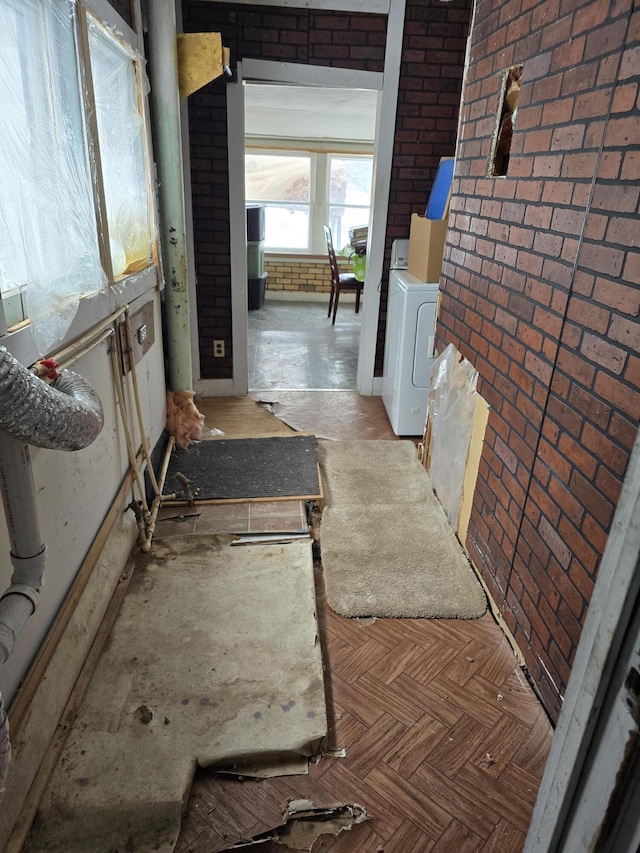 corridor with brick wall and washer / clothes dryer