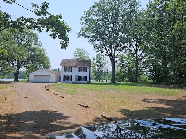 colonial-style house featuring a front yard, a detached garage, and an outdoor structure