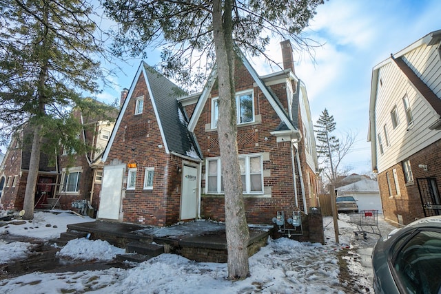 view of front of house with a garage, roof with shingles, a chimney, and brick siding