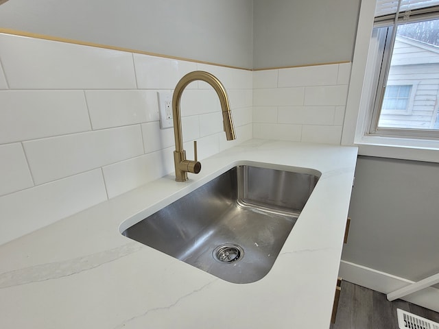 details with a sink, light stone countertops, and decorative backsplash