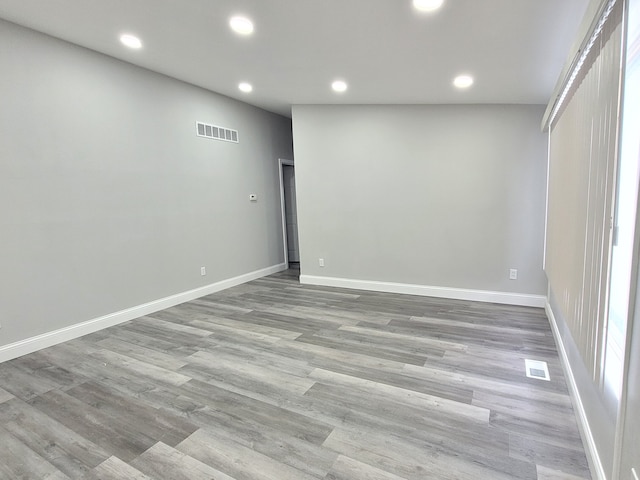 spare room featuring light wood finished floors, baseboards, visible vents, and recessed lighting