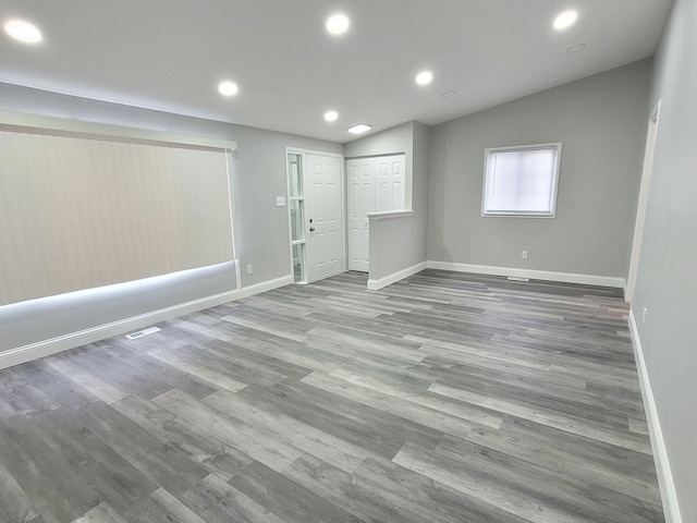 spare room featuring recessed lighting, vaulted ceiling, baseboards, and wood finished floors