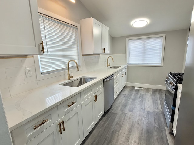 kitchen with stainless steel appliances, white cabinetry, a sink, and light stone counters