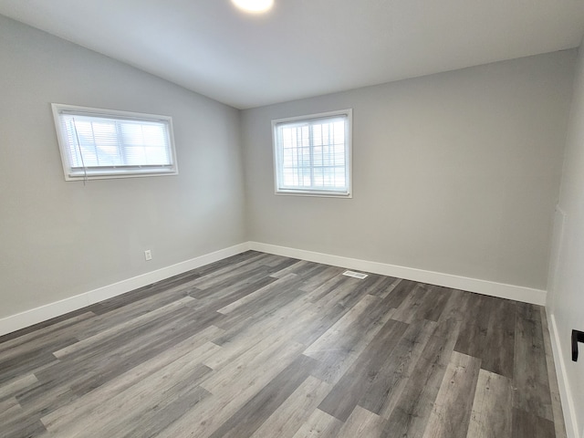 empty room featuring baseboards, vaulted ceiling, and wood finished floors