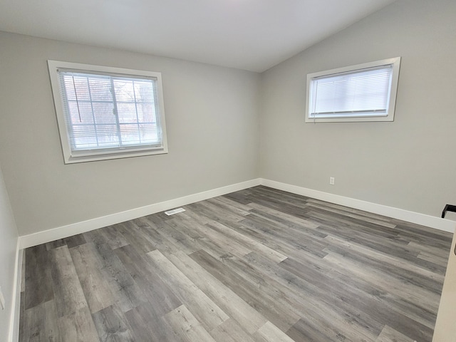 unfurnished room featuring a wealth of natural light, wood finished floors, visible vents, and baseboards