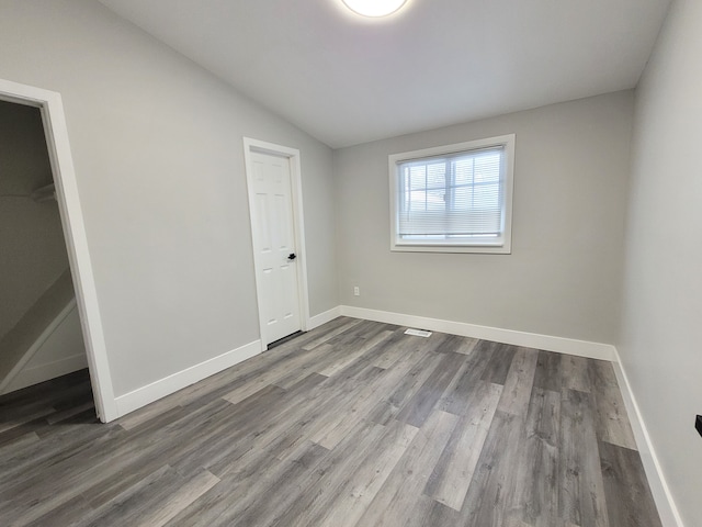 unfurnished bedroom featuring vaulted ceiling, baseboards, and wood finished floors