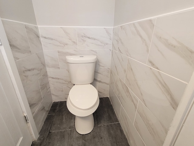 bathroom with toilet and tile walls