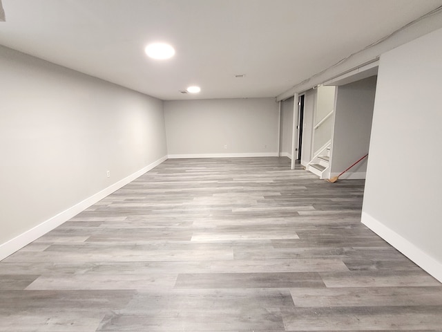 finished below grade area featuring recessed lighting, stairway, baseboards, and wood finished floors