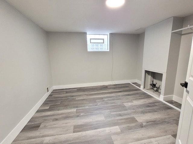 basement featuring visible vents, baseboards, and wood finished floors