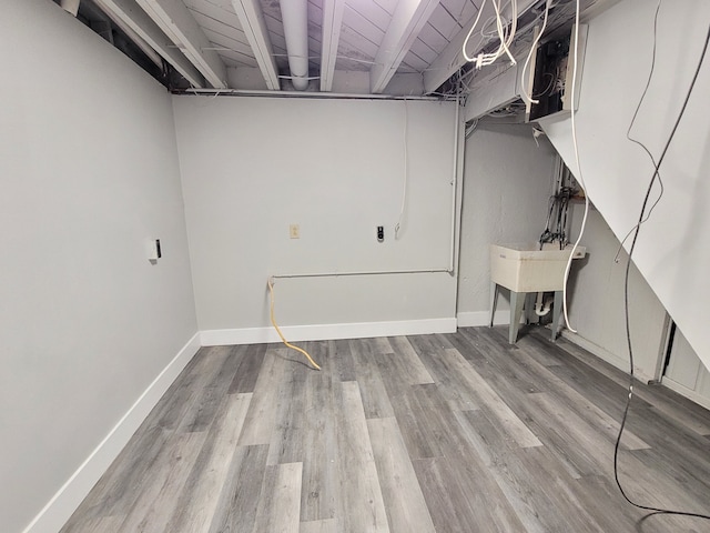 unfinished basement featuring a sink, wood finished floors, and baseboards