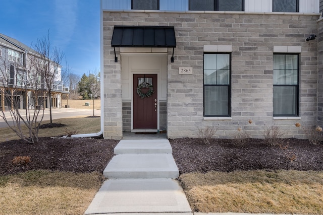 doorway to property featuring board and batten siding and stone siding