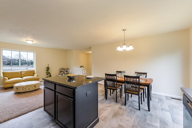 kitchen featuring dishwasher, dark countertops, a center island, decorative light fixtures, and a chandelier