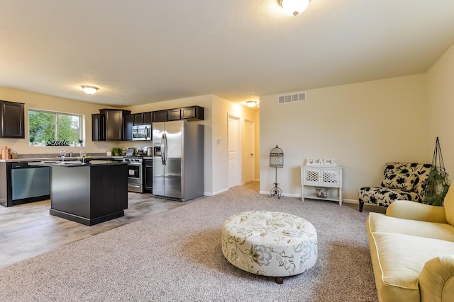 kitchen with visible vents, light colored carpet, open floor plan, a center island, and stainless steel appliances