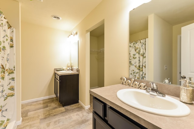 full bathroom with visible vents, two vanities, a sink, and a walk in closet