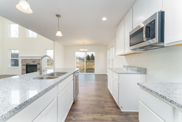 5124 Huggins Rd, Michigan Center, MI 49254 - kitchen with white cabinets, appliances with stainless steel finishes, light stone countertops, pendant lighting, and a sink