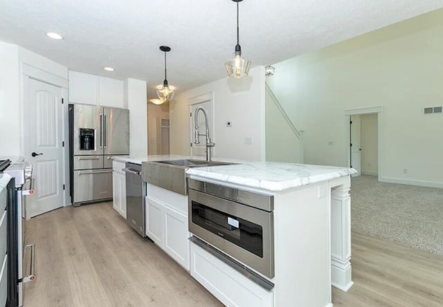 5124 Huggins Rd, Michigan Center, MI 49254 - kitchen featuring visible vents, white cabinets, hanging light fixtures, a kitchen island with sink, and stainless steel appliances
