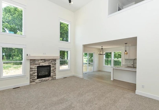 5124 Huggins Rd, Michigan Center, MI 49254 - unfurnished living room featuring light carpet, a fireplace, a towering ceiling, and a healthy amount of sunlight