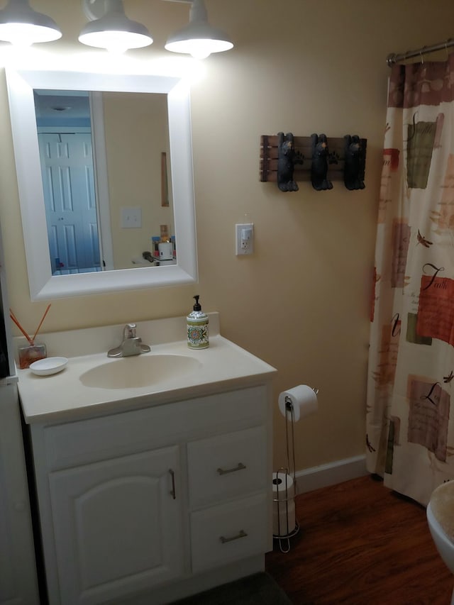 bathroom with toilet, wood finished floors, vanity, baseboards, and a shower with curtain