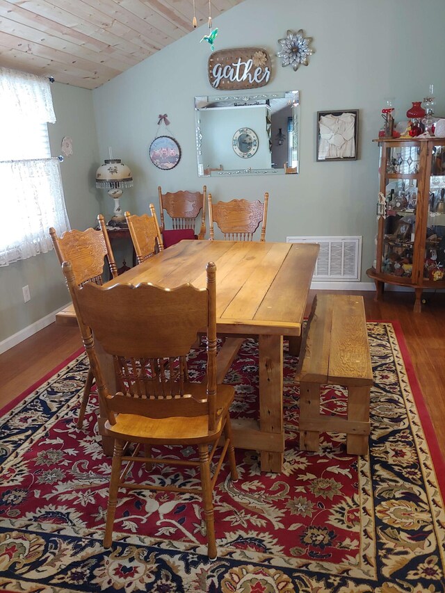 dining room featuring wood finished floors, visible vents, baseboards, vaulted ceiling, and wooden ceiling