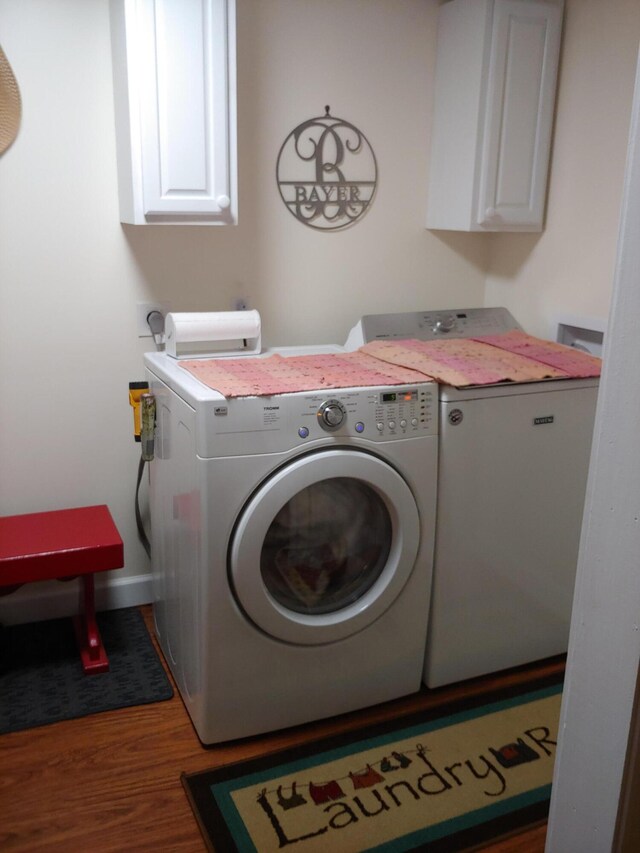 washroom with baseboards, cabinet space, independent washer and dryer, and wood finished floors