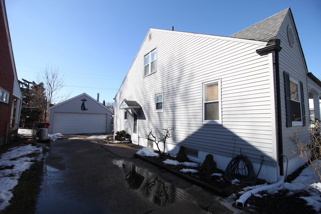 view of snowy exterior with a garage and an outdoor structure