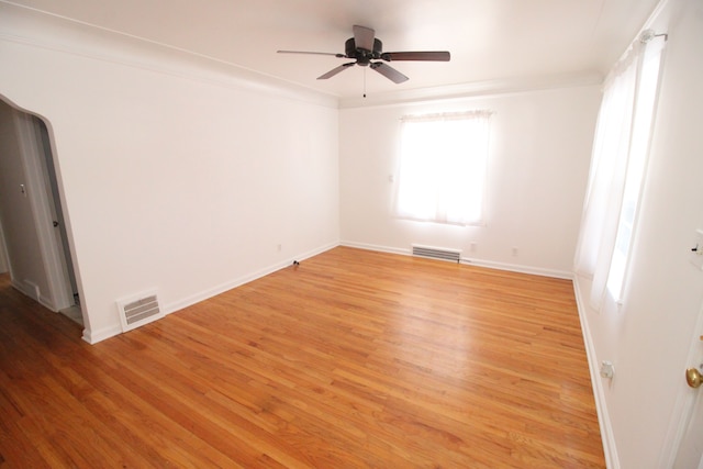 spare room with ornamental molding, a ceiling fan, visible vents, and light wood-style floors