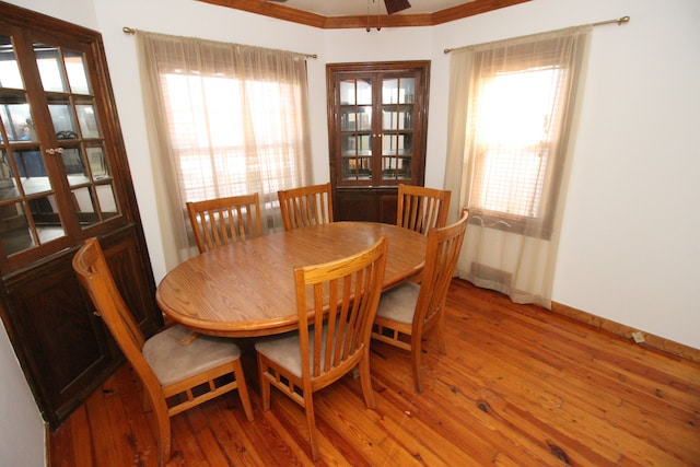 dining space with french doors, crown molding, baseboards, and wood finished floors