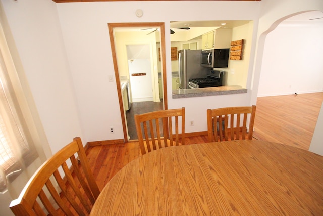 unfurnished dining area with light wood-style floors, baseboards, and arched walkways