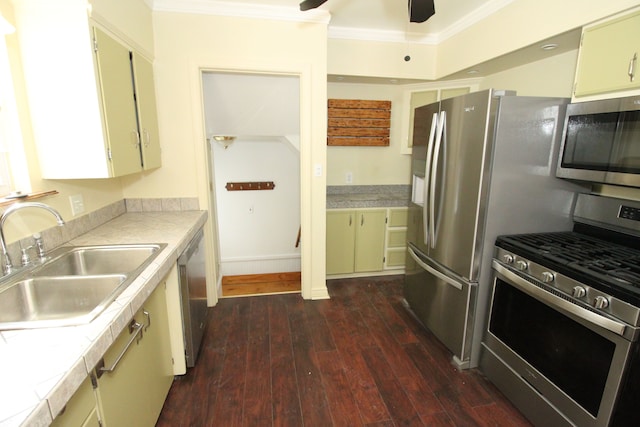 kitchen with ceiling fan, dark wood-type flooring, stainless steel appliances, crown molding, and a sink