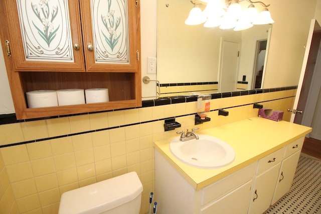 bathroom featuring toilet, a wainscoted wall, tile walls, and vanity