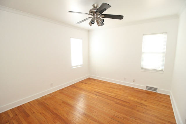 unfurnished room with ornamental molding, plenty of natural light, light wood-style flooring, and baseboards