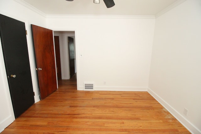 empty room with baseboards, ornamental molding, visible vents, and light wood-style floors