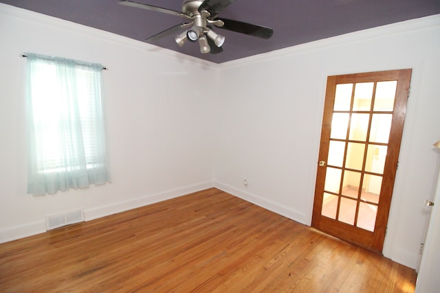 empty room with ceiling fan, visible vents, baseboards, ornamental molding, and light wood-type flooring