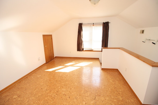 additional living space featuring lofted ceiling, visible vents, and baseboards