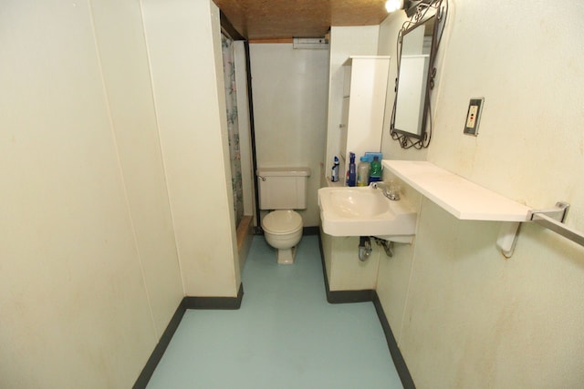 bathroom with a sink, concrete floors, and toilet