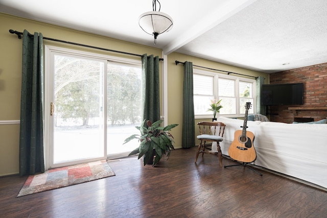 living area featuring beam ceiling, a textured ceiling, and wood finished floors