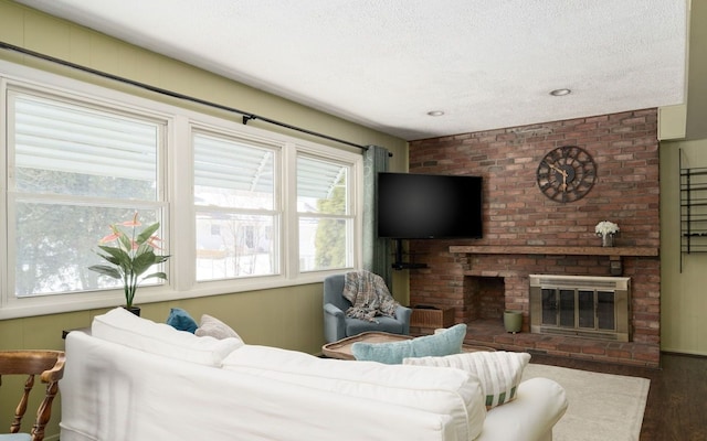 living area featuring a fireplace, a textured ceiling, and wood finished floors