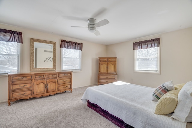 bedroom featuring light carpet, multiple windows, and a ceiling fan