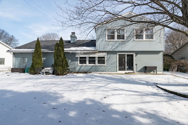 snow covered back of property with a chimney