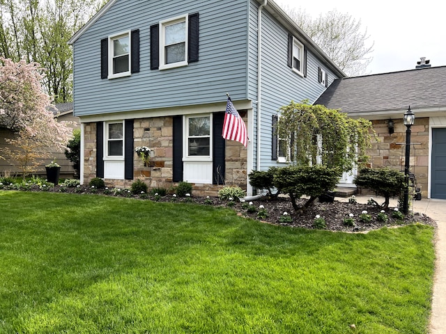 view of front facade with stone siding, a front lawn, an attached garage, and driveway