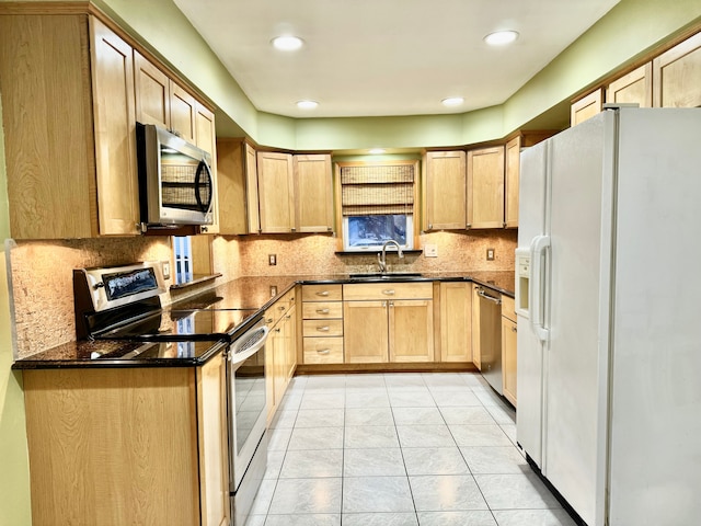 kitchen with tasteful backsplash, stainless steel appliances, light brown cabinetry, a sink, and light tile patterned flooring