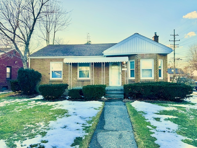 view of front of home with a shingled roof, a chimney, and brick siding