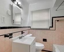 full bath with toilet, tile walls, and vanity