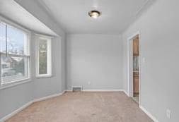 empty room featuring light colored carpet, visible vents, and baseboards