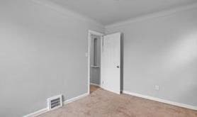 spare room with carpet flooring, visible vents, and baseboards