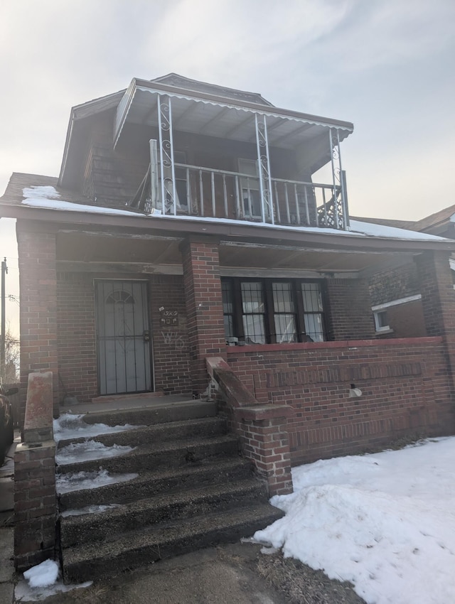 view of front of house with brick siding and a balcony