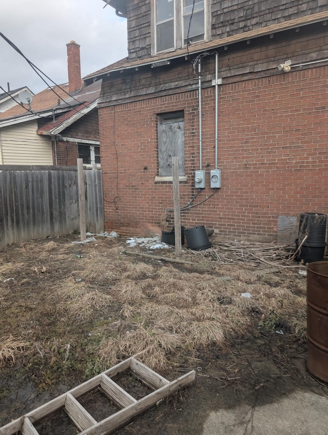 view of side of property featuring brick siding and fence